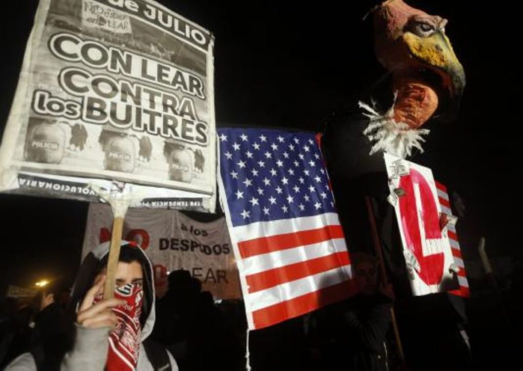 A protester, rallying against layoffs holds a placard that reads "With Lear against the vultures" next to a mock vulture, in front of the factory of U.S. automotive supplier Lear on the outskirts of Buenos Aires